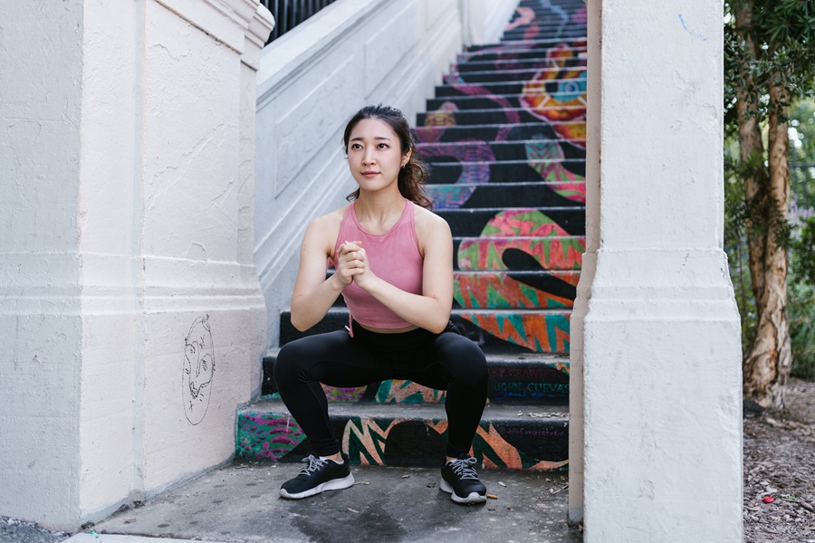 Transform 20 Calendar Schedule and Workout Tips a Woman Doing Squats in Front of Colorful Stairway Outside