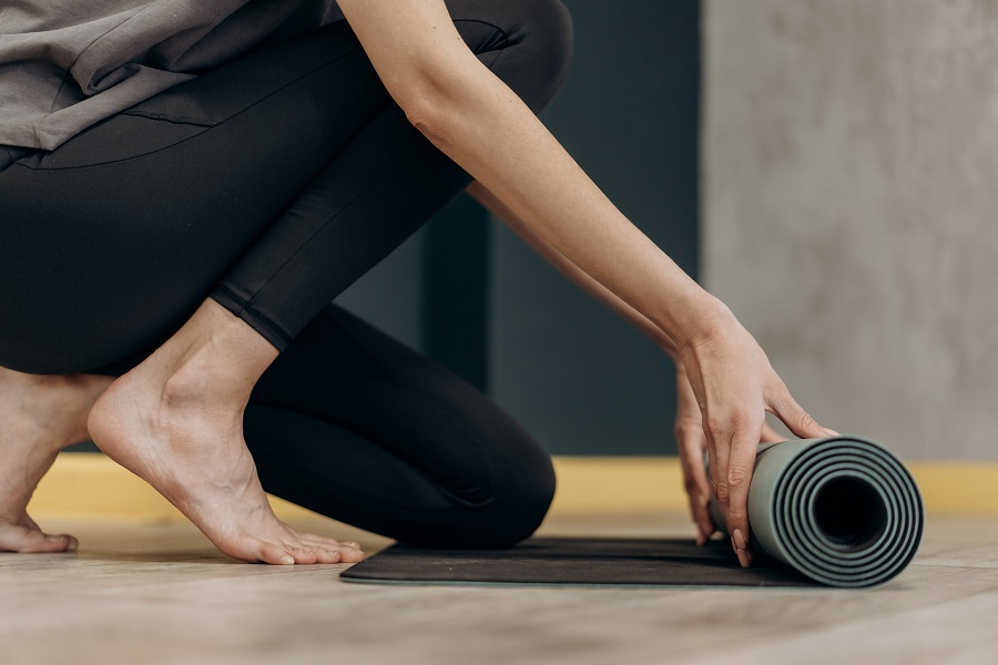 Do Anywhere No Weights Needed At Home Workouts Close Up of a Woman's Feet and Legst as She Rolls Out a Fitness Mat