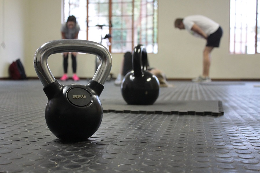 Transform 20 Week 1 Workouts and Tips Close Up of a Kettle Bell in a Gym with People Working Out in the Background