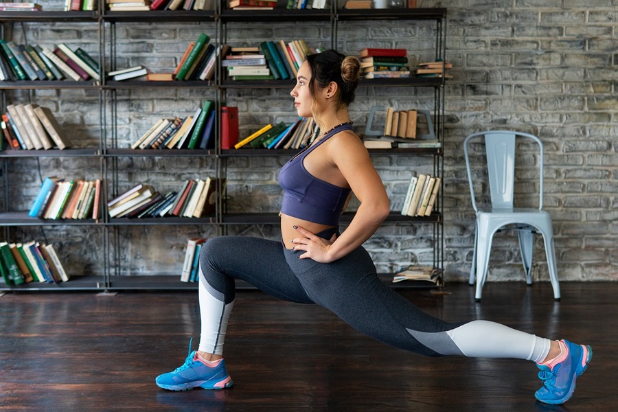 Transform 20 BONUS with Weights, Workouts, and Tips a Woman Doing Lunges in a Room with a Bookshelf Behind Her Against a Brick Wall