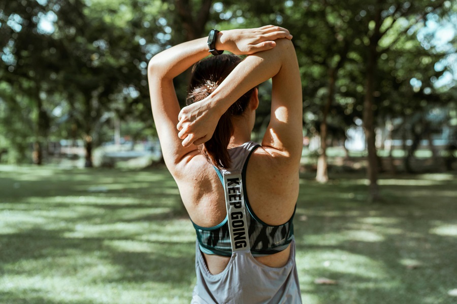 Transform 20 Week 5 Workouts and Tips a Woman in a Park Stretching Before a Workout