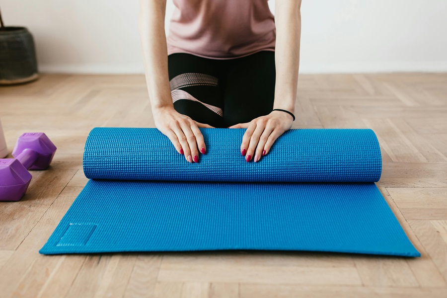 Transform 20 Week 5 Workouts and Tips a Woman Rolling Up a Blue Yoga Mat