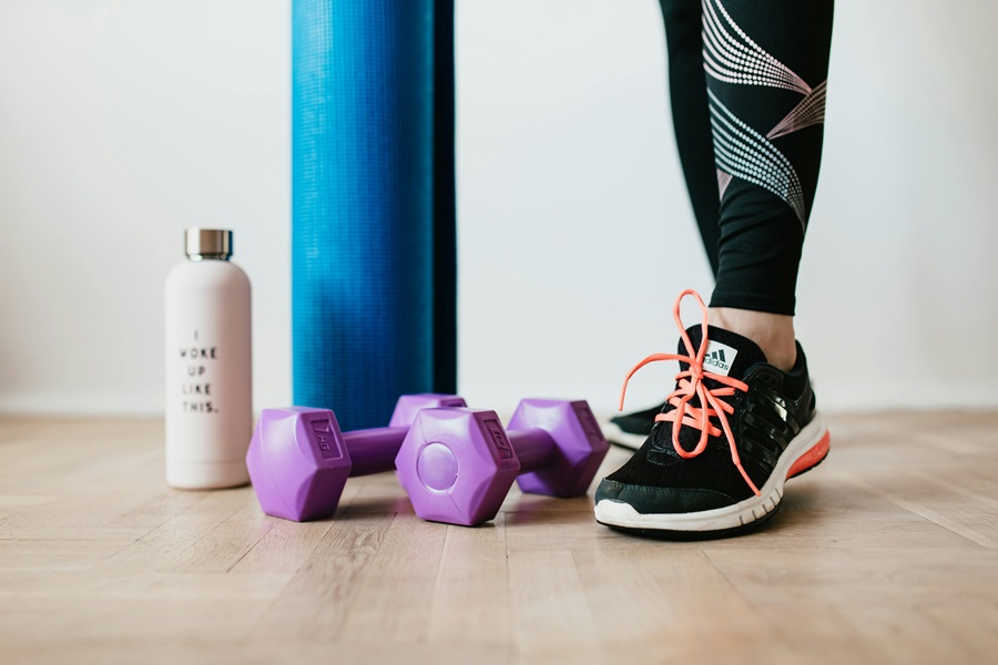 Transform 20 Week 5 Workouts and Tips Close Up of a Woman's Shoes Next to Dumbbells, a Yoga Mat, and a Water Bottle