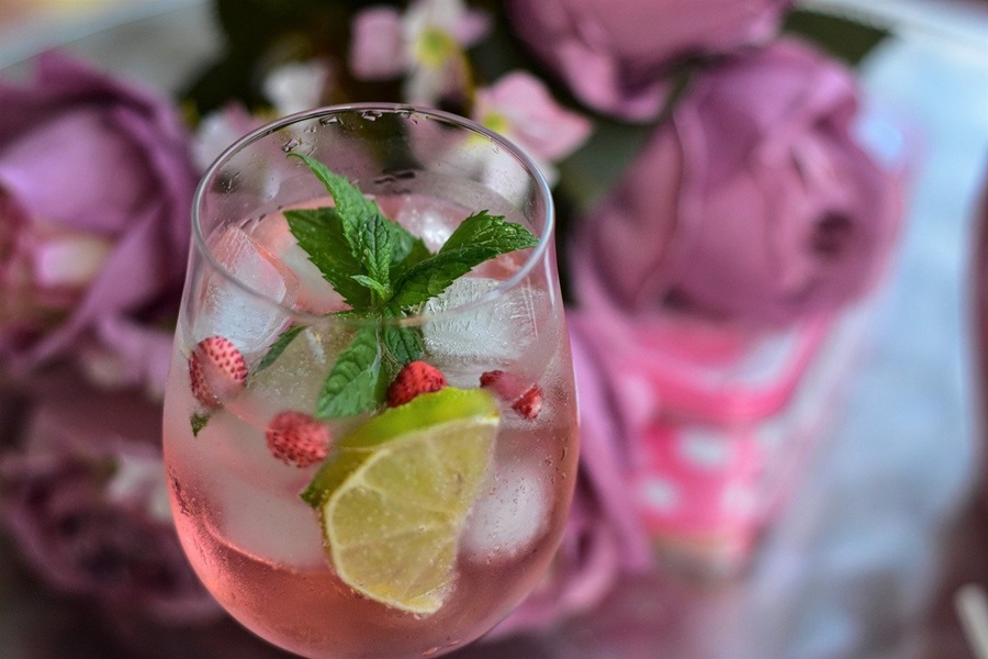 Delightfully Smooth Casamigos Anejo Recipes Close Up of a Cocktail in a Glass Garnished with Lime, Fruit, and Mint Leaves