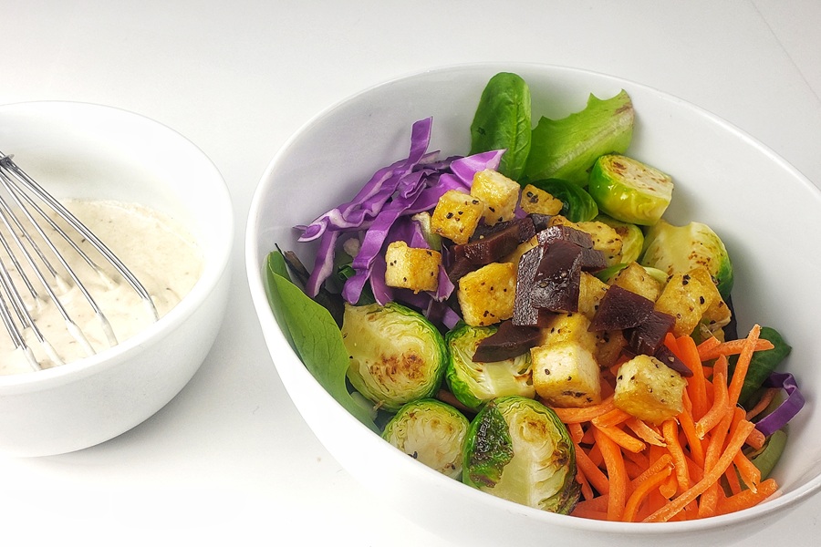 2B Mindset Buddha Bowl with Dairy Free Sauce a Buddha Bowl Next to a Small Bowl of Sauce with a Whisk Inside