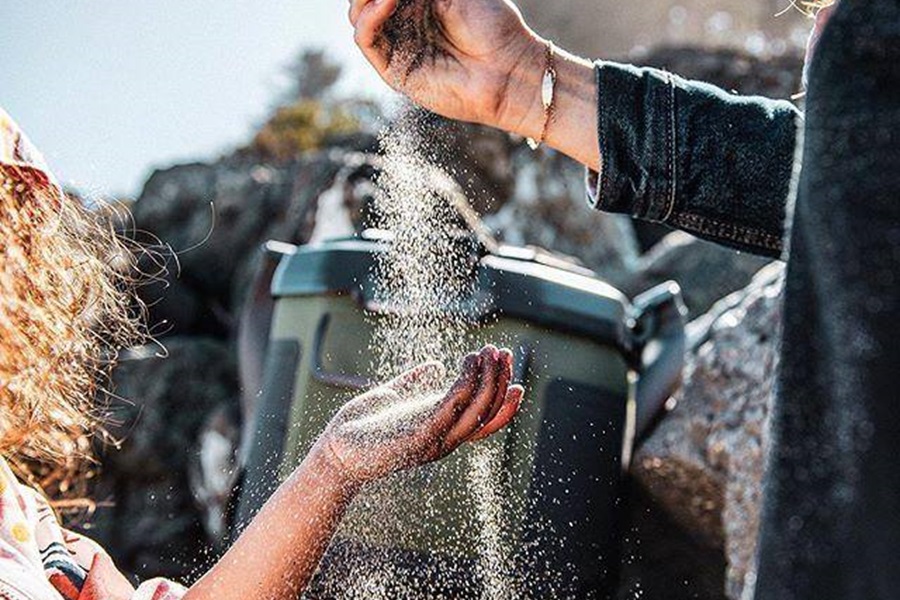 Otterbox Trooper Coolers Features and Review Close Up of Sand Being Poured Into a Child's Hand with a Cooler in the Background