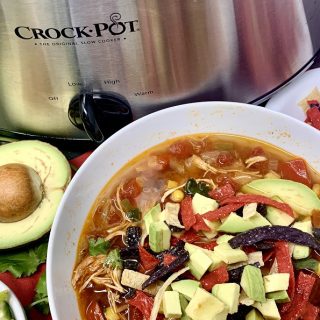 Slow Cooker Chicken Tortilla Soup Close Up of a Bowl of Soup Next to a Crockpot
