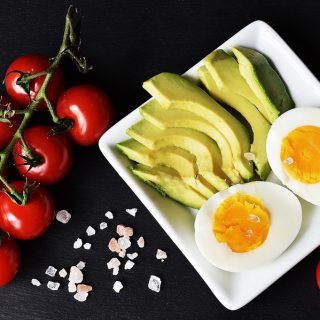 Ketogenic Diet Food List Hard Boiled Eggs, Avocado, and Tomatoes Sliced on a Plate