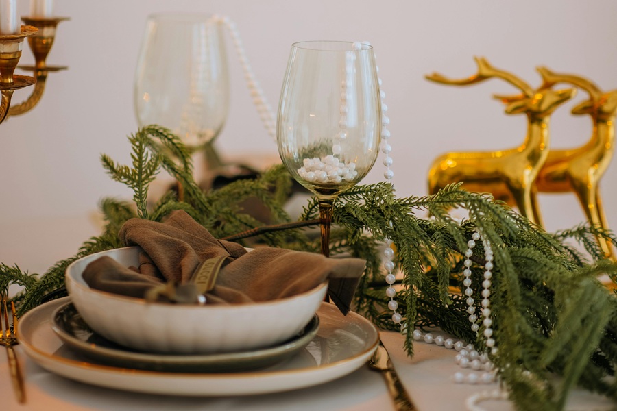 Low-Carb Holiday Recipes Table Setting in White and Gold with Golden Reindeer Statues as a Centerpiece on a Table