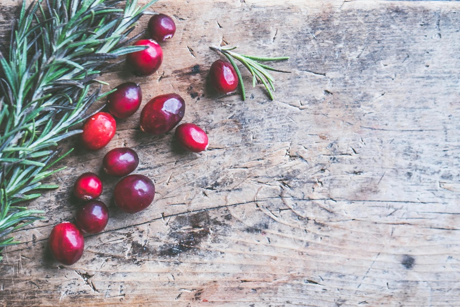 Low-Carb Holiday Recipes Close Up of a Handful of Cranberries on a Wooden Surface with some Pine Sprigs