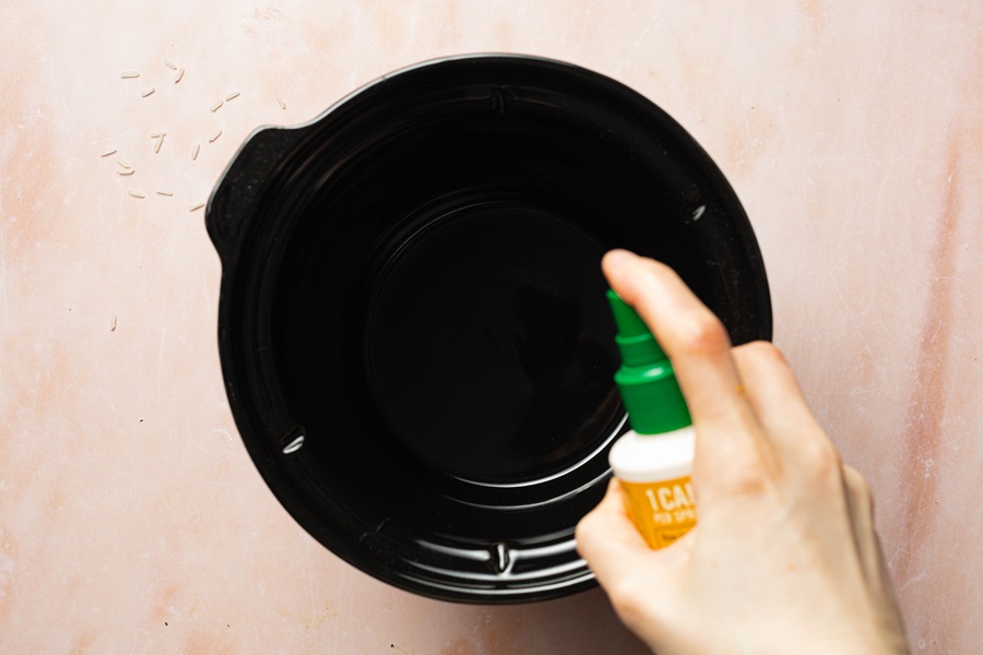 Salsa Chicken and Rice Recipe View of a Hand Spraying the Inside of a Crockpot with Butter Spray