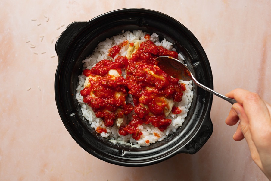 Salsa Chicken and Rice Recipe Salsa Being Spooned On To Chicken and Rice in a Crockpot