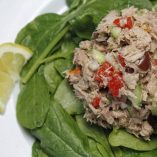 Low Carb Tuna Salad on a Bed of Spinach with a Lemon Next to it.
