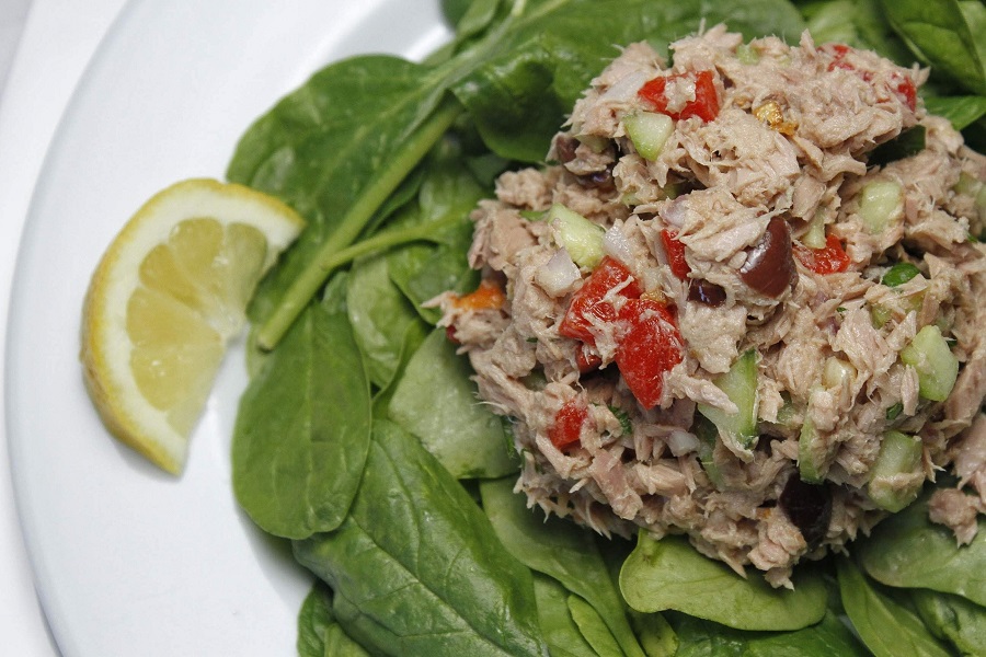 Low Carb Tuna Salad on a Bed of Spinach with a Lemon Next to it.