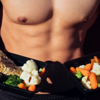 Low Carb Lunch Ideas Shirtless Man Holding To Plates of Healthy Food