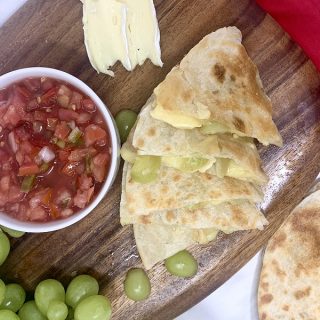 Brie and Grape Quesadilla Recipe Quesadilla Pieces on a Cutting Board with a Cup of Salsa Next to It