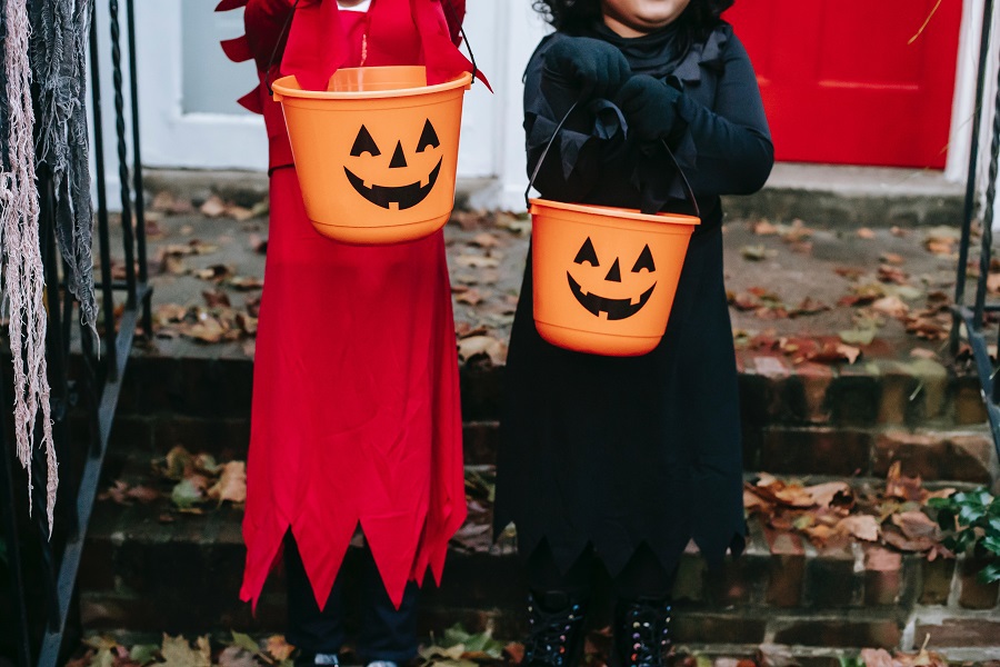 Halloween Recipes for All Ages Two Kids in Costumes Holding Jack O Lantern Buckets Standing on a Porch. 