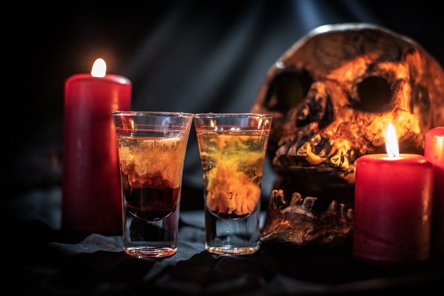 Halloween Cocktails Close Up of Two Shots in Front of a Skull and a Red Lit Candle