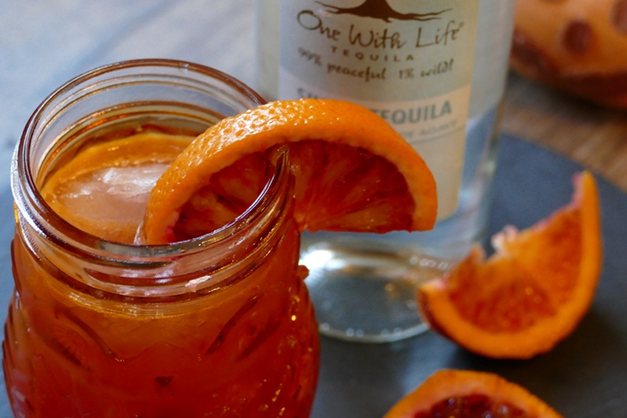 Halloween Cocktails Close Up of a Blood Orange Margarita with a Bottle of Vodka in the Background