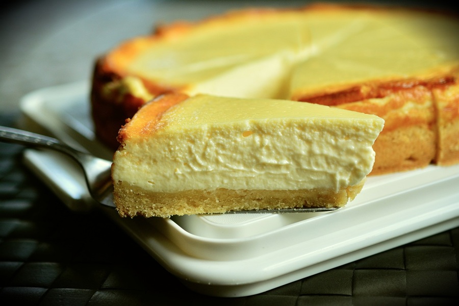 Easy Crockpot Thanksgiving Desserts Close Up of a Slice of Cheesecake with The Rest of the Cake in the Background