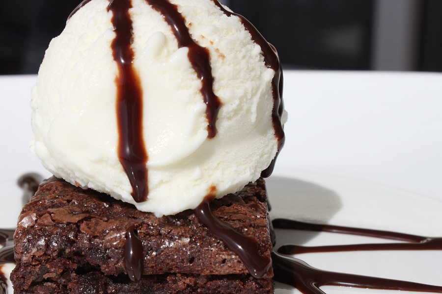 Easy Crockpot Thanksgiving Desserts Close Up of a Chocolate Brownie Topped with Vanilla Ice Cream and Drizzled with Chocolate Syrup