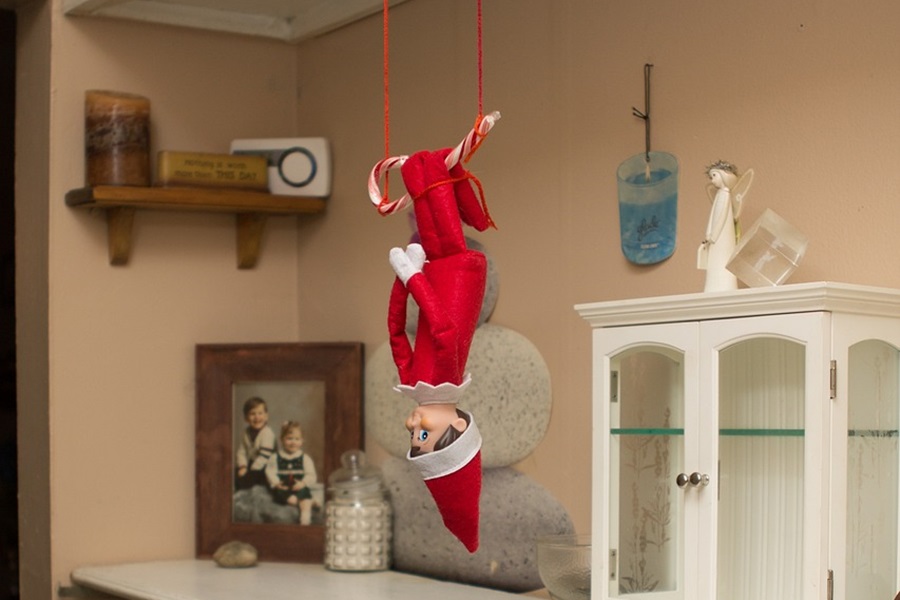 Quick Tips for when your Elf on the Shelf Didn't Move Close Up of an Elf Hanging Upside Down From a Cabinet in a Kitchen