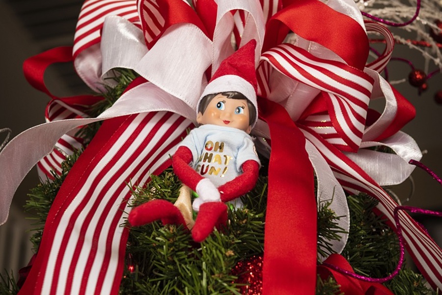 Quick Tips for when your Elf on the Shelf Didn't Move Close Up of an Elf in a Christmas Tree with a Red and White Ribbon Behind It