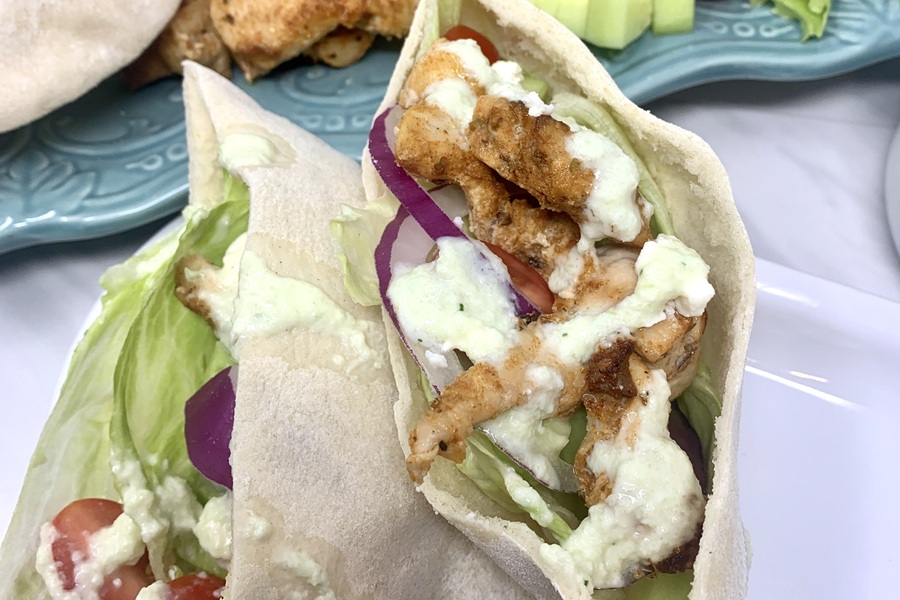 Chicken and Tzatziki in Pita Pockets Next to a Serving Platter Filled with Ingredients