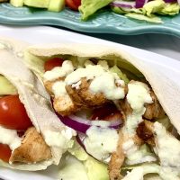 Chicken and Tzatziki in Pita Pockets Close Up of Pita Pockets Filed with Chicken, Lettuce, Onions, Tomatoes, and Tzatziki Sauce