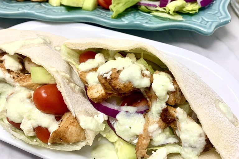 Chicken and Tzatziki in Pita Pockets Close Up of Pita Pockets Filed with Chicken, Lettuce, Onions, Tomatoes, and Tzatziki Sauce