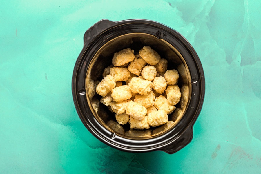 Slow Cooker John Wayne Casserole with Tater Tots Overhead View of a Crockpot with a Layer of Tater Tots