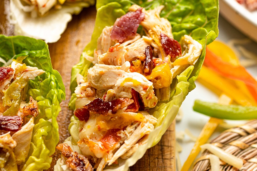 Crockpot Chicken and Bacon Keto Close Up of a Chicken and Bacon Lettuce Wrap on a Wooden Cutting Board