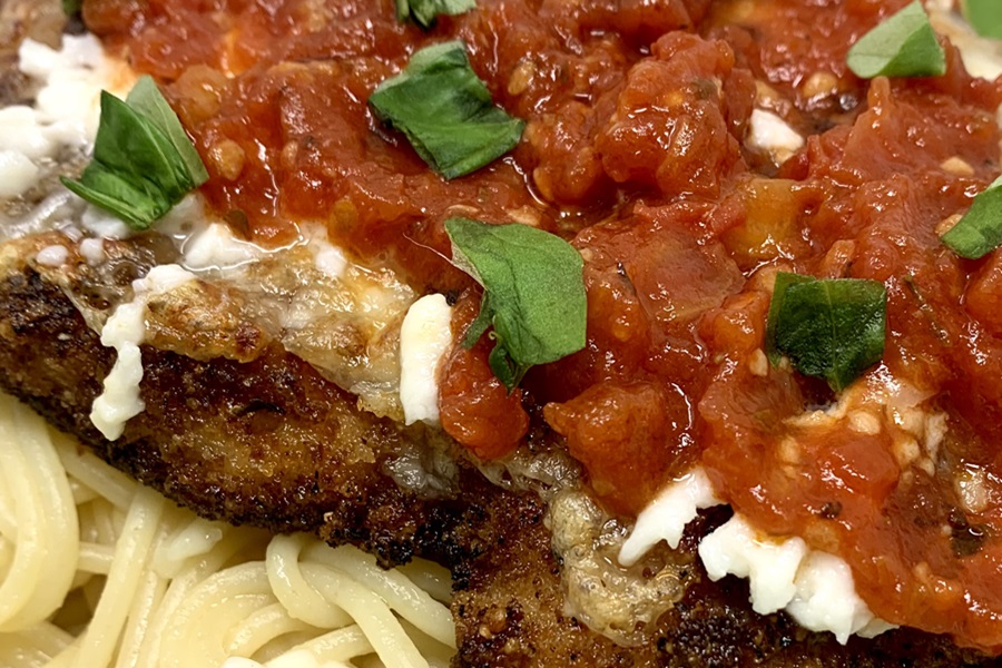 Best Panko Chicken Parmesan Recipe Close Up of the Cooked Chicken on a Bed of Spaghetti Covered in Tomato Sauce and Cheese