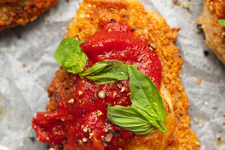 Best Panko Chicken Parmesan Recipe Close Up of a Breaded Chicken Breast with Sauce and Basil