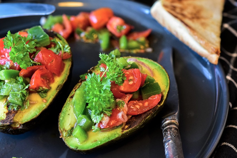Best of Cinco de Mayo Recipes Close Up of an Avocado Cut in Half with Tomatoes and Cilantro