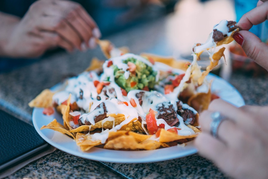 Cinco de Mayo Foods for Fiestas a Plate of Nachos with People Taking Chips from it