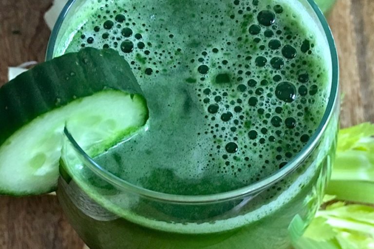 Green Juice Recipe Close Up of Green Juice in a Glass Garnished with a Slice of Cucumber