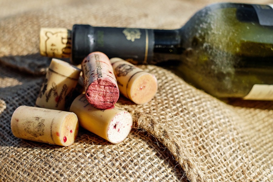 DIY Wine Gifts for Women a Wine Bottle and a Handful of Wine Corks on a Burlap Sack