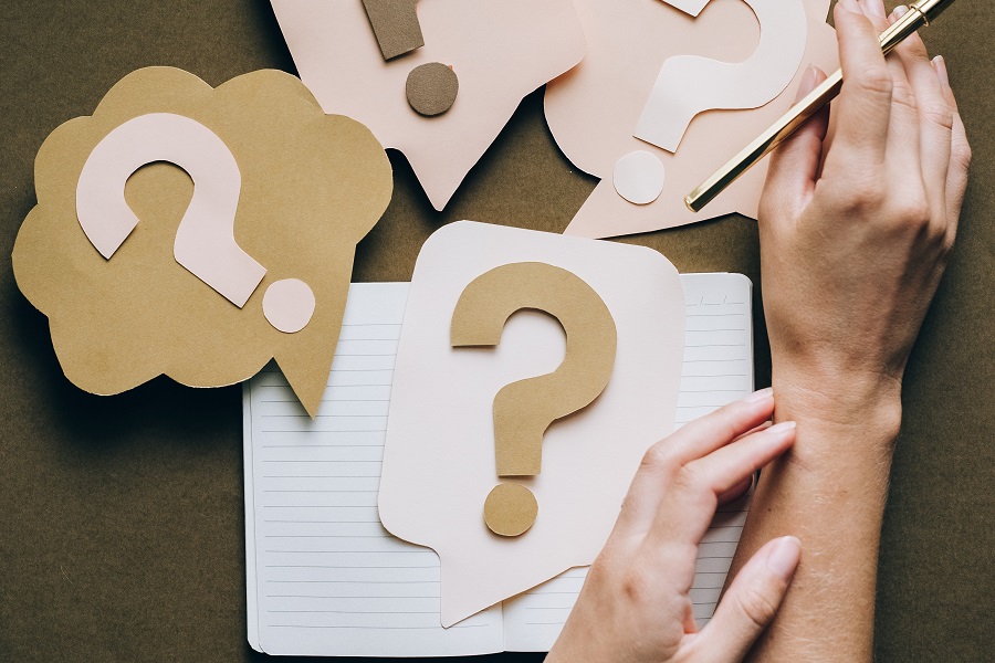 Amazon Echo Show Paper Question Marks Scattered on a Desk with a Person's Hands Holding One of Them