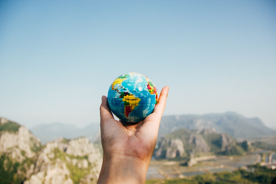 Amazon Echo Show a Person's Hand Holding Up a Small Globe Toy