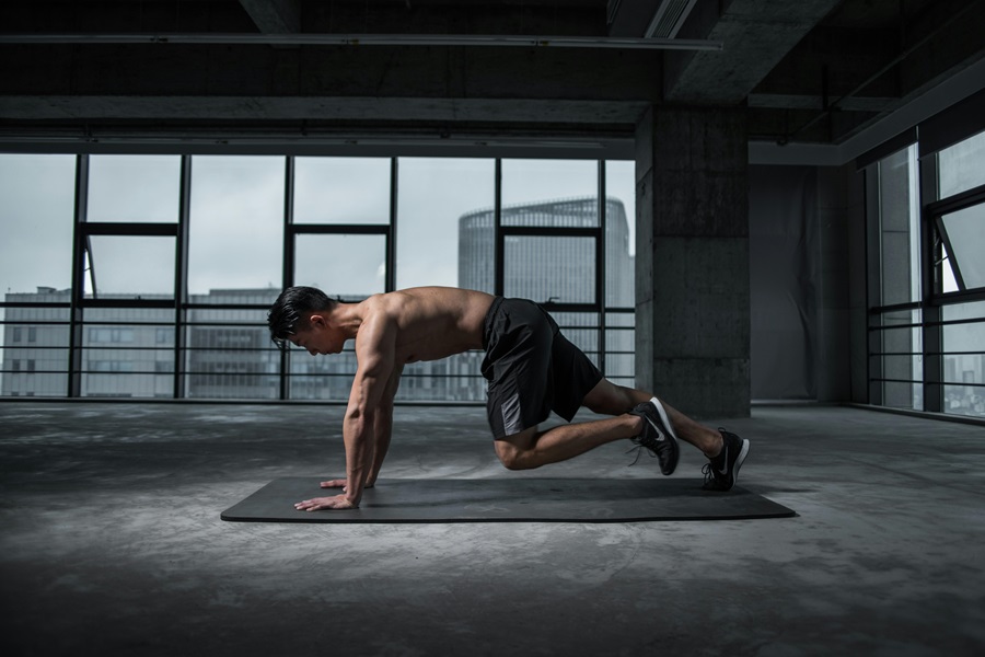 25 Oblique Workouts to Do at Home a Man Doing Mountain Climbers in a Studio Gym