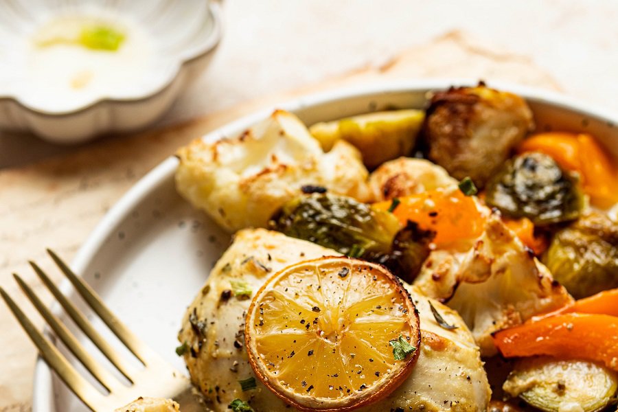 Dairy Free Dinner Recipes Close Up of a Roasted Chicken breast with a Lemon Slice On Top and Roasted Veggies Next to it