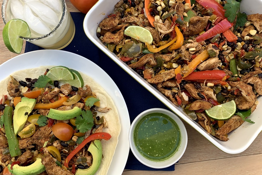 Dairy Free Slow Cooker Chicken Fajitas Recipe Overhead View of a Serving Tray of Chicken Fajitas Next to a Plate with a Tortilla on it Topped with Chicken Fajitas 