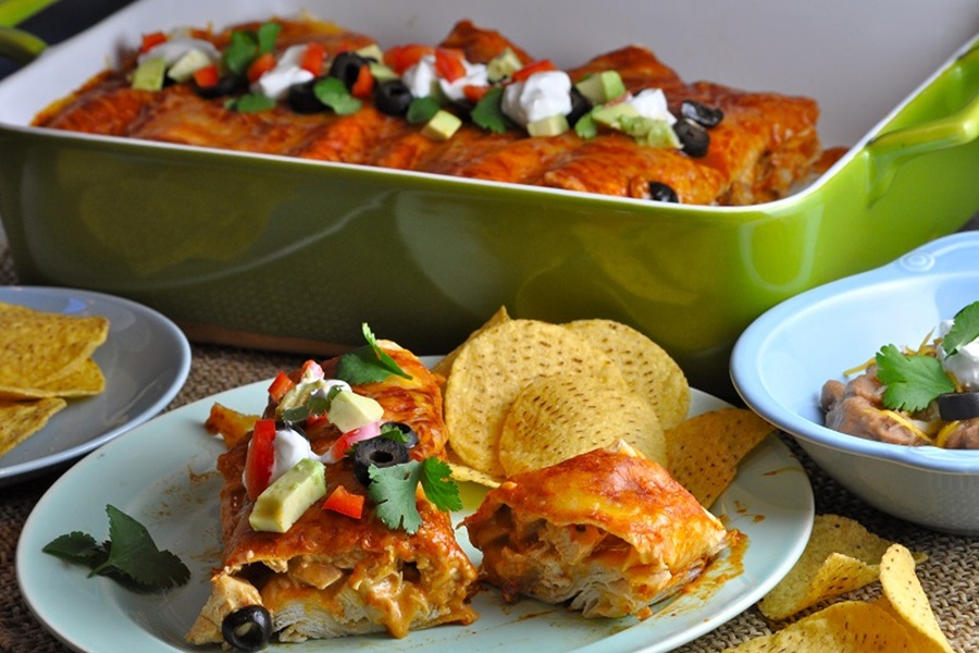 Easy Chicken Enchiladas Recipe Enchiladas on a Plate with a Baking Dish Filled with Enchiladas in the Background