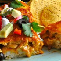 Easy Chicken Enchiladas Recipe Close Up of an Enchilada Cut in Half on a Plate with Tortilla Chips