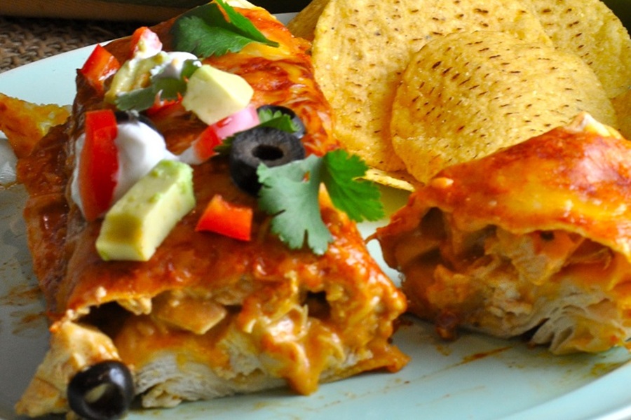 Easy Chicken Enchiladas Recipe Close Up of an Enchilada Cut in Half on a Plate with Tortilla Chips