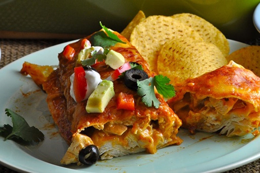 Easy Chicken Enchiladas Recipe an Enchilada Cut in Half on a White Plate with Tortilla Chips