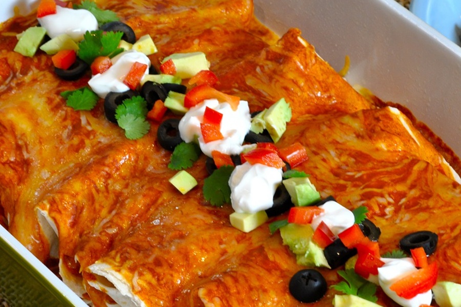 Easy Chicken Enchiladas Recipe Enchiladas in a Baking Dish Topped with Tomatoes, Avocado, and Sour Cream