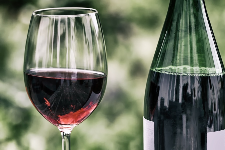 Wine Glasses for the Beach or Pool Close Up of a Wine Glass Filled Halfway with Red Wine Next to a Bottle of Red Wine