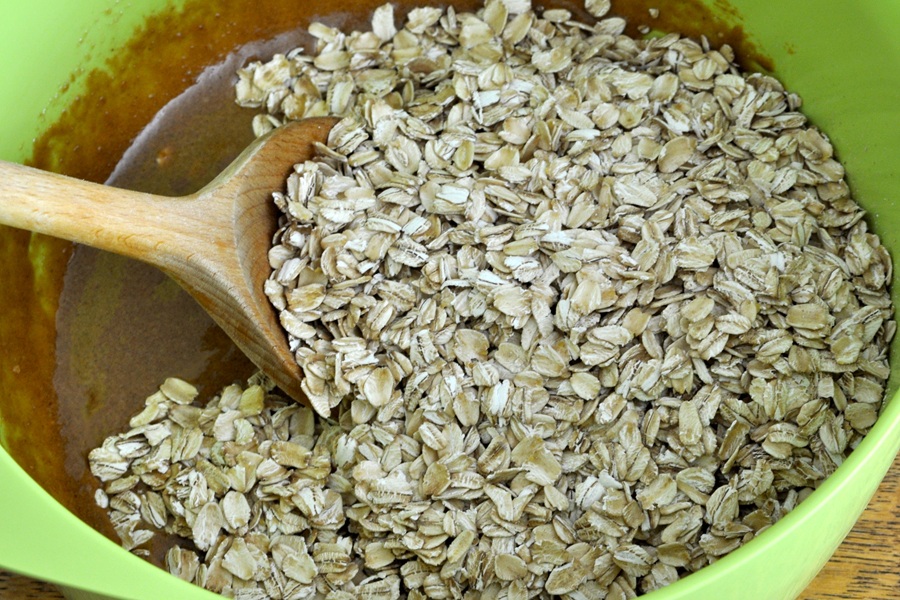 Peanut Butter Oatmeal Balls View of Peanut Butter and Oats in a Green mixing Bowl with a Wooden Spoon